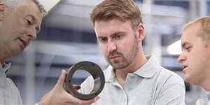 Three men looking at a tool