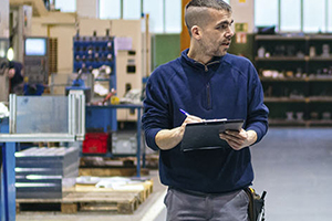 worker walking in shop with pad and paper on hand
