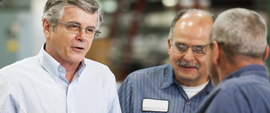 three men discussing metalworking