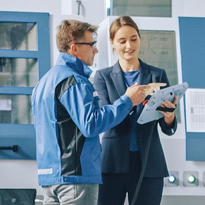 two workers discussing in front of a machine