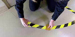 man putting down safety stripe marking tape
