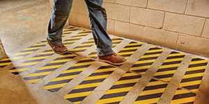 man walking on floor with yellow and black tape