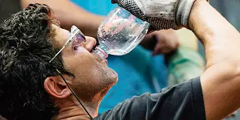 worker in safety glasses drinking water from a bottle