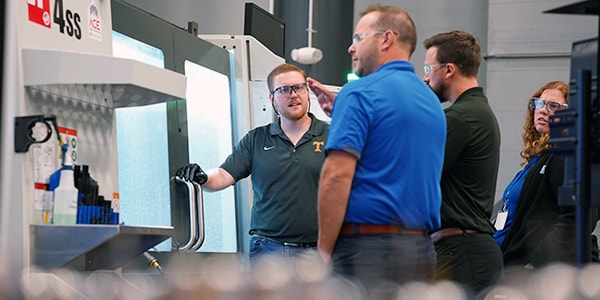 workers talking in front of cnc machine