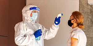a person in PPE taking a woman's temperature